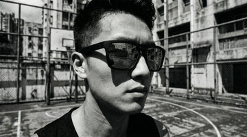 Person adjusting lightweight sunglasses outdoors in humid tropical morning conditions.