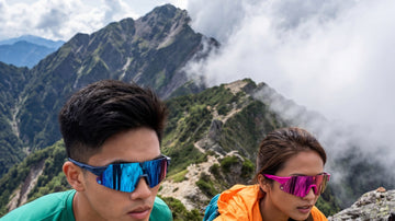 Two hikers wearing performance sunglasses on a mountain trail under changing cloud and sun
