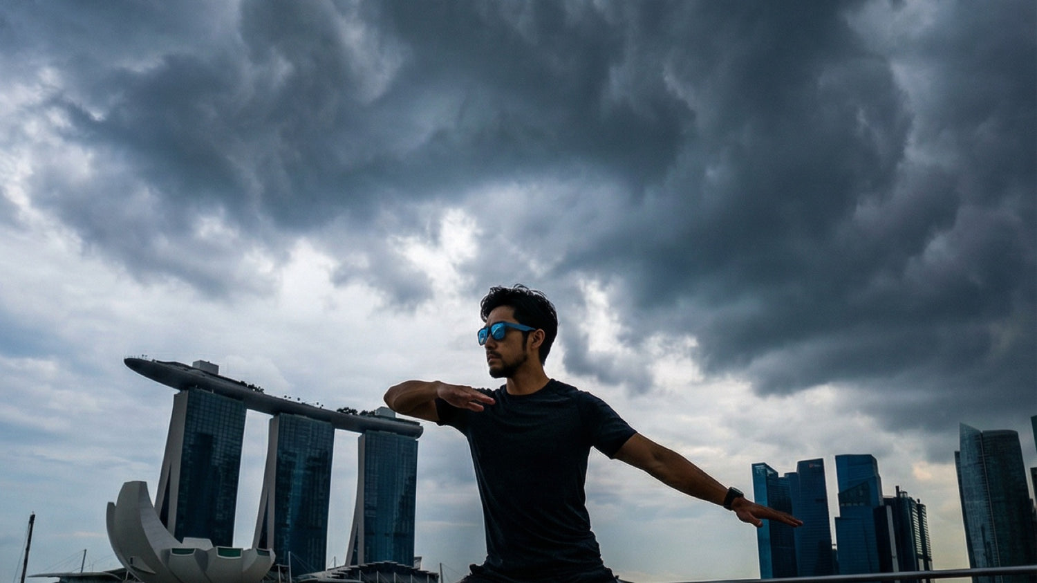 Runner wearing performance sunglasses beside Singapore's waterfront under a cloudy sky