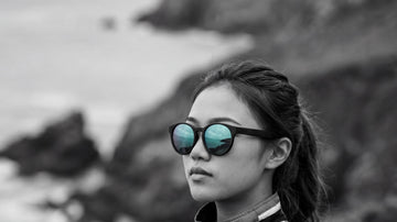 Woman wearing 2nu sunglasses with reflective lenses near the coast, showing lens tint and glare control for outdoor use