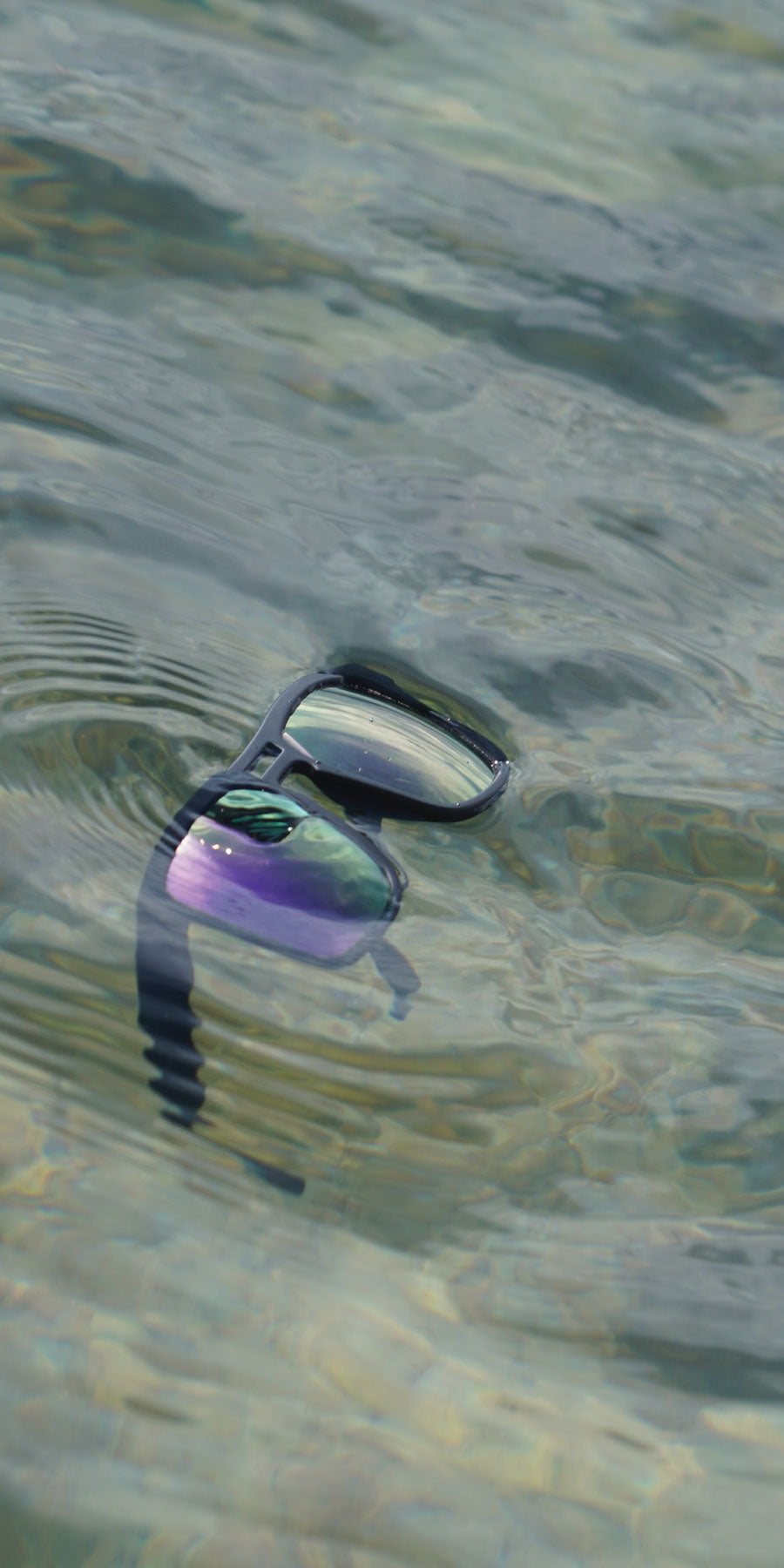 Floating sunglasses on blue water surface during a paddle boarding session